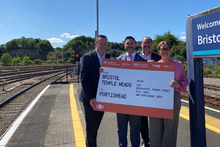4 people holding a giant ticket from bristol to portishead on a train platform